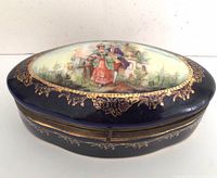 Front angled view of cobalt blue porcelain trinket box with Rococo scene on lid