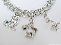 Front view showing bracelet and three charms (Sagittarius, stork with baby, office chair)