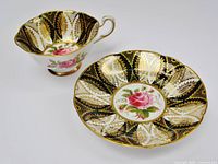 Cup and saucer displaying interior rose pattern and gold on black design
