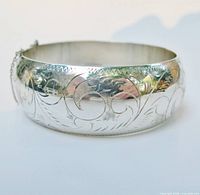 Side view of domed etched sterling bangle showing swirl pattern and safety chain