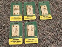 Front view of five sealed brass-plated 3x3 door hinges on retail cards