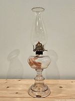 Full front view of entire clear glass oil lamp on wood surface