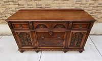 Front view of carved oak buffet showing drawers, doors and hardware