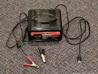 Front view of charger showing brand label, handle, power cord, and clamp leads