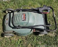 Top view of Black & Decker electric lawnmower showing green deck, wheels, foldable black handle