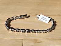 Bracelet laid out showing gemstones and clasp with tag indicating S.Silver M.Sapphire 6cts