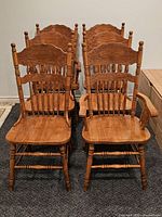 Six matching solid wood press-back chairs grouped together