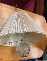 Full view of swag lamp showing pleated shade, glass ball accent, brass hardware