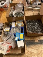 Overall view of three cardboard trays filled with loose nails, screws, bolts and packaged fasteners