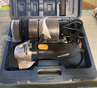 Open case showing grinder, discs, handle, wrench, guard