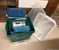 Group of totes with lids nested, white laundry basket visible