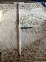 Full view of assembled floor-to-ceiling tension pole with grab bar laid on carpet
