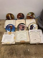 Seven Norman Rockwell plates displayed with COAs and boxes