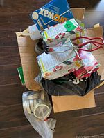 Overhead view of box containing jar grabber, Bernardin pectin boxes, Parowax, bag of rings and lids
