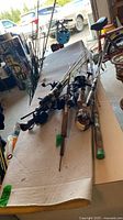All seven fishing rods with reels laid on table