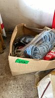 Box containing blue-white rope in plastic, straps package and other ropes