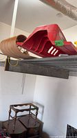 Red plastic sled and wooden toboggan on storage shelf