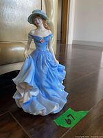 Full view of figurine front, blue dress and hat visible