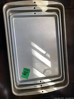 Four nesting Wilton baking sheet pans showing light gray nonstick finish and rim holes