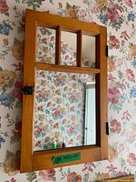 Front view of wood-framed mirror showing windowpane design and latch
