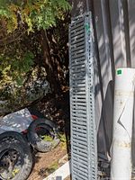 Full length view of one galvanized steel perforated ramp leaning upright outdoors