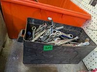 Black bin filled with assorted wrenches and tools