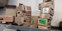 Multiple Senco staple boxes stacked on shelf, taped and worn