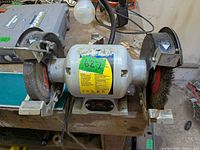 Overall view of bench grinder mounted on workbench showing both wheels and switch