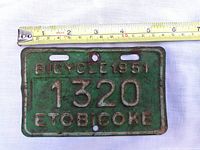 Front of green embossed 1951 Etobicoke bicycle plate, ruler indicating size