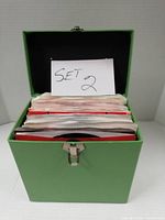 Green carrying case open showing stack of sleeved records