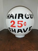 Front of milk glass globe showing HAIRCUT 25¢ SHAVE text