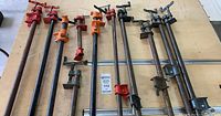 Eight pipe clamps laid on tabletop with two guide rails