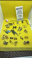 Overview of assorted earrings on yellow background with auction sign