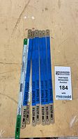 Seven hacksaw blades laid flat showing branding, colors and pinned ends