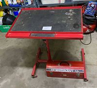 Red adjustable work stand with perforated top and Mastercraft toolbox underneath