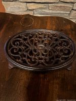 Top view of ornate cast iron trivet showing scrollwork and rusted surface