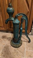 Full view of cast-iron pump, blue-green paint, mounted on wooden disk