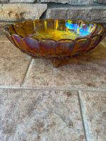 Side view showing marigold iridescence and scalloped rim of three-footed bowl