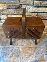 Closed wooden cantilever sewing box on legs, front view