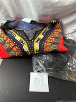 Folded red dashiki shirt with accessories bag beside it
