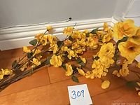 Group of three yellow artificial blossom stems on hardwood floor