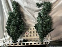 Two artificial spiral tabletop Christmas trees placed in white lattice basket