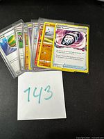 Stack of sleeved Pokémon cards in toploaders, Lost Vacuum front, lot marker 143 visible