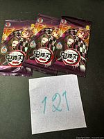 Front view of three sealed Demon Slayer card packs with artwork