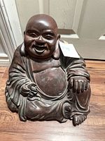 Front view of seated Laughing Buddha statue showing facial features, robe and hand positions