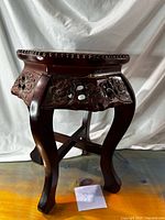 Full view of plant stand showing carved floral apron, cabriole legs, reddish finish