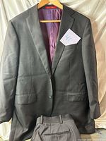 Front view of charcoal jacket on hanger with trousers displayed below