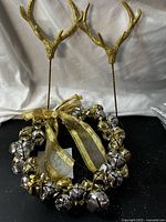 Wreath of metallic bells with ribbon and two antler picks displayed upright