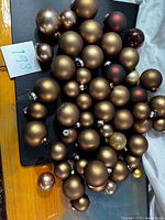 Spread of assorted metallic copper, bronze and brown glass ball ornaments with metal caps