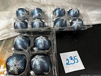 Top view of three trays holding 12 matte steel-blue snowflake ornaments